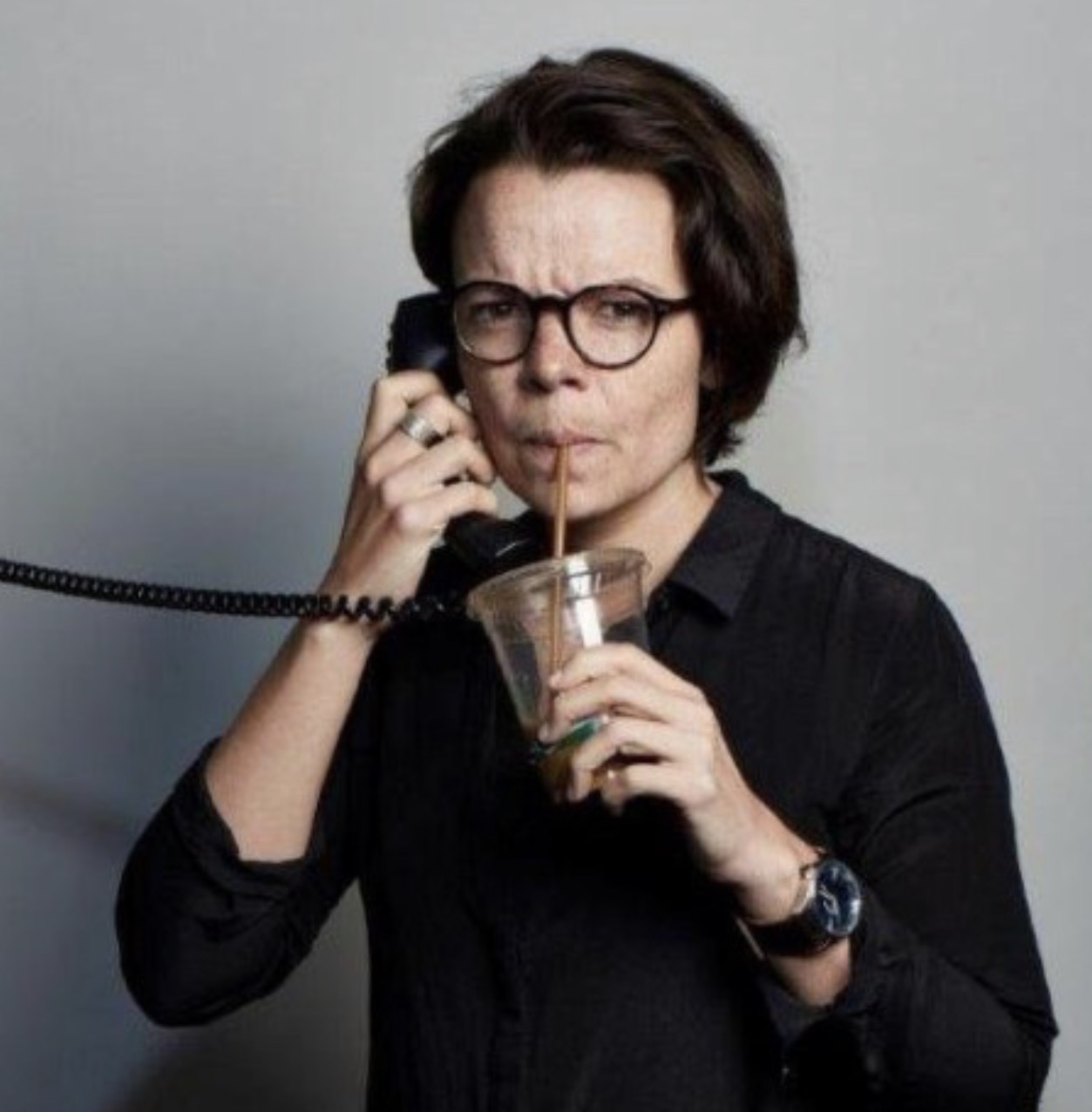 Darla Horn holding a phone while drinking an iced coffee
